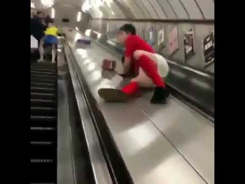 A Guy Takes a Header While Sliding Down the Middle of an Escalator